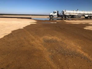 Industrial vacuum truck positioned beside a large area of collected wastewater