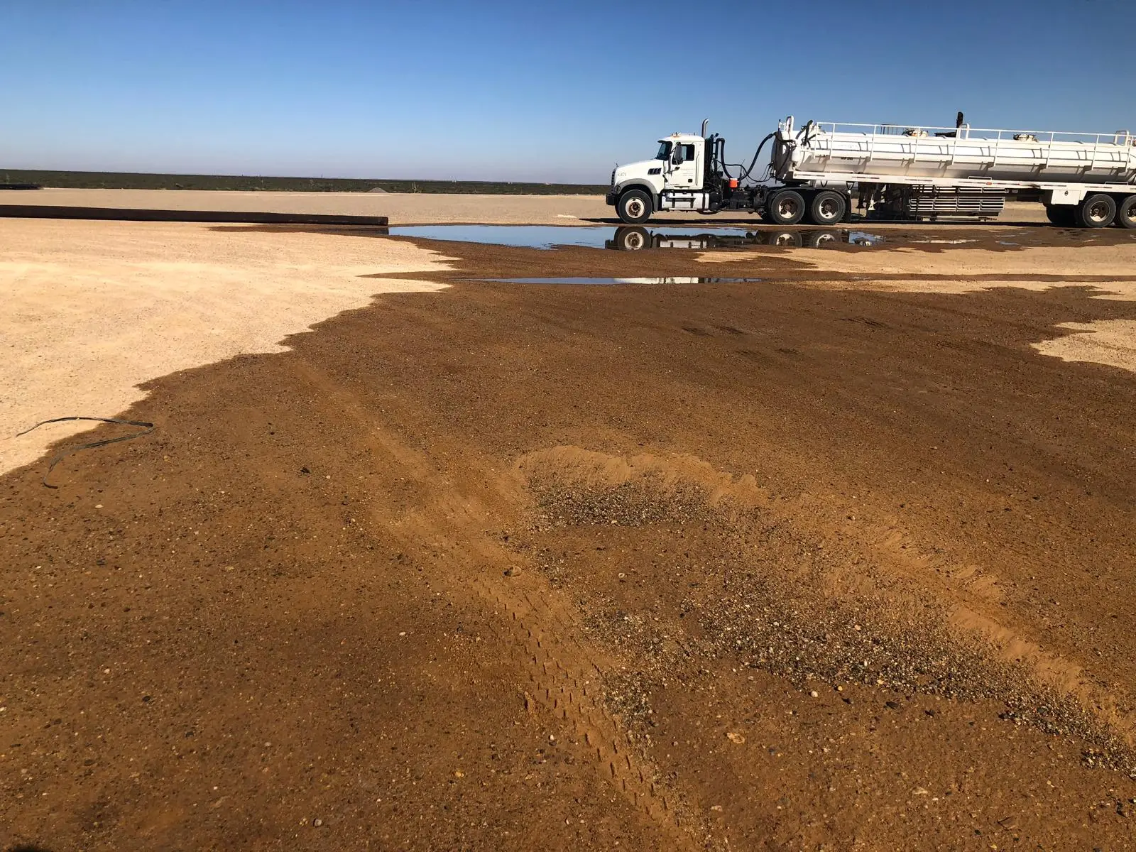 Industrial vacuum truck positioned beside a large area of collected wastewater